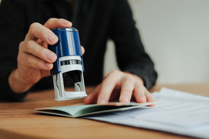 Man border control worker puts a stamp in the passport. Tourism, boarding control. Copy space